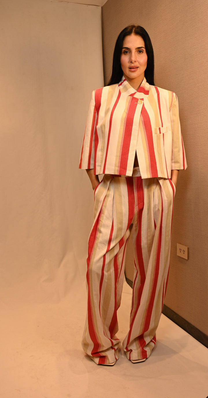 Set blazer cropped a rayas rojas, beige y marfil de frente, manos en los bolsillos: cuello mao y cierre cruzado de un botón